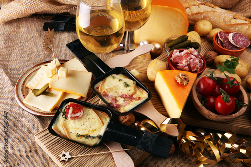 Photography Delicious traditional Swiss melted raclette cheese on diced boiled or baked potato served in individual skillets
