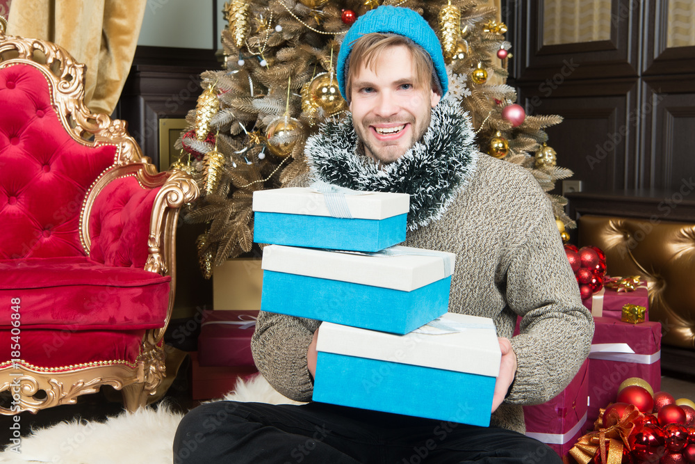 Man in hat, sweater smile with wrapped presents