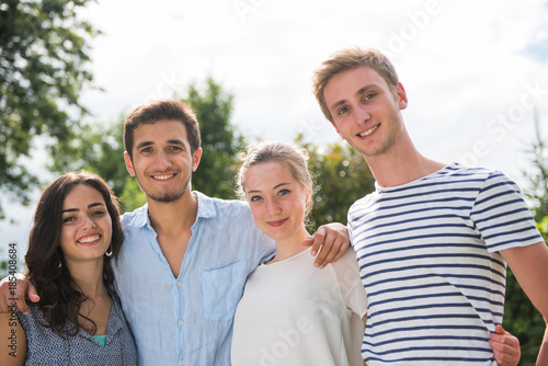 Portrait of four young people outside, they look at the camera