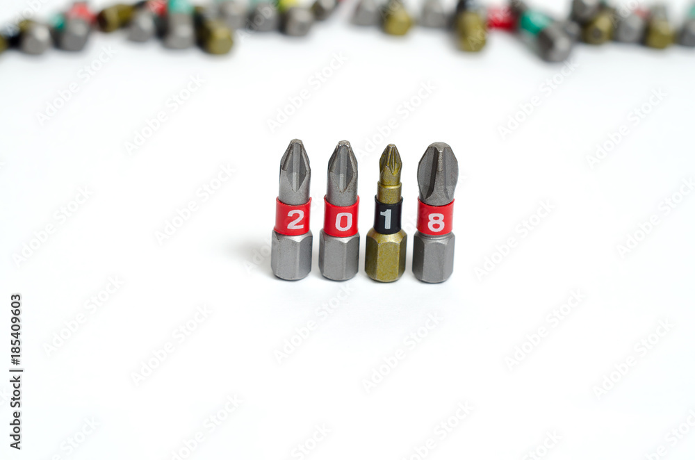 Set of heads for screwdriver (bits) in New year order 2018. Tools collection close up, blurred white background.