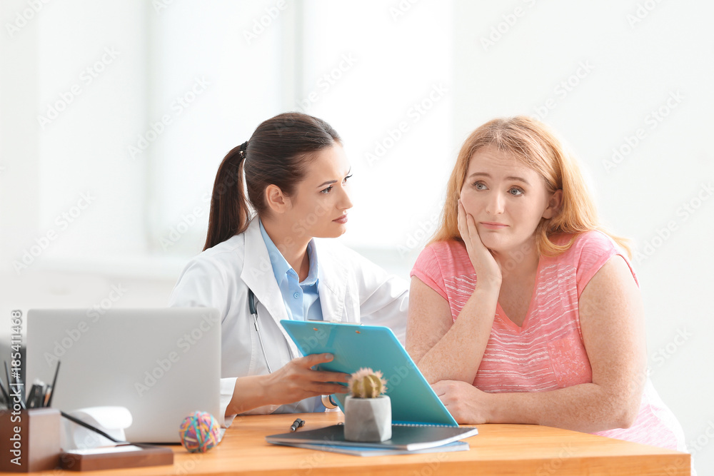 Young female doctor consulting overweight woman in clinic Young female doctor consulting overweight woman in clinic