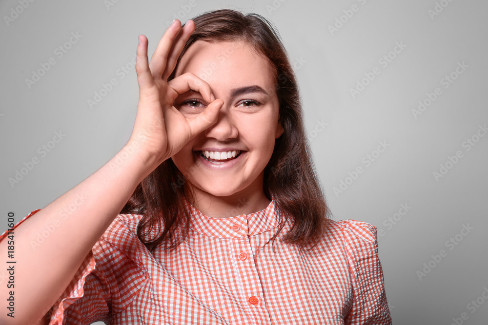 Beautiful smiling woman showing OK gesture on light background Beautiful smiling woman showing OK gesture on light background