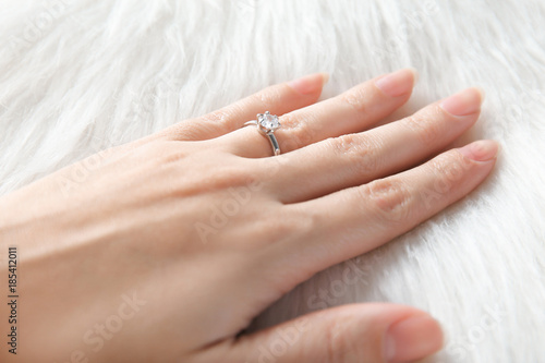Woman's hand with luxury engagement ring on fur, closeup