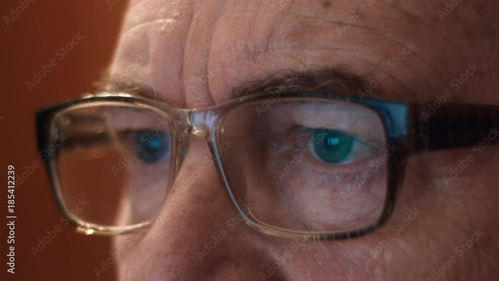 An Elderly Man With Glasses Eyes Looking At The Monitor, Surfing The Internet.