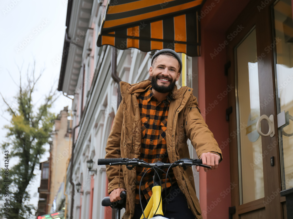 Attractive young hipster riding bicycle on city street Attractive young hipster riding bicycle on city street