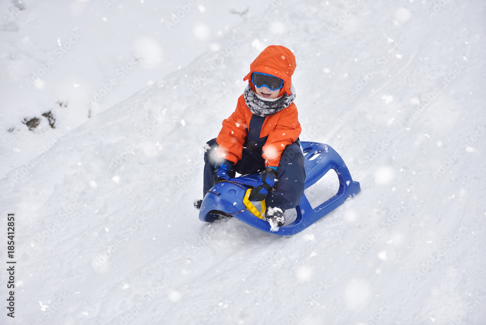 Little boy riding on snow slides in winter time Little boy riding on snow slides in winter time