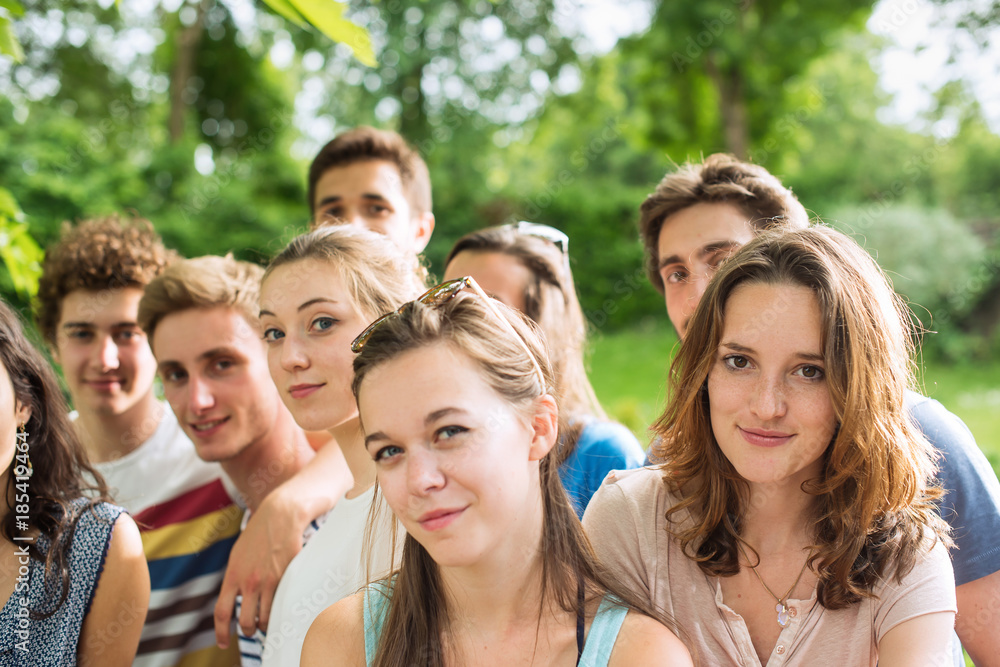 Group of young people in a park, they are looking at camera Group of young people in a park, they are looking at camera