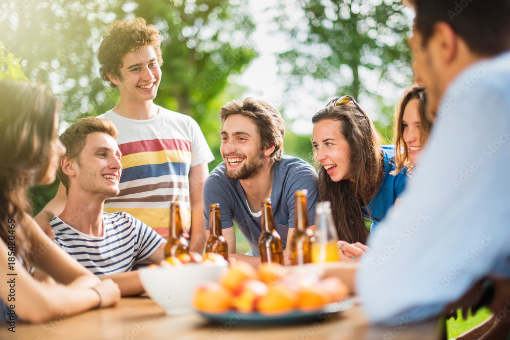 Group of young people gathered around a table outside to chat Group of young people gathered around a table outside to chat