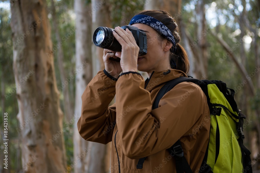 Hiker woman clicking a photo in forest