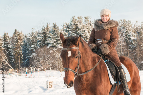 Woman in brown dress and brown horse in a winter