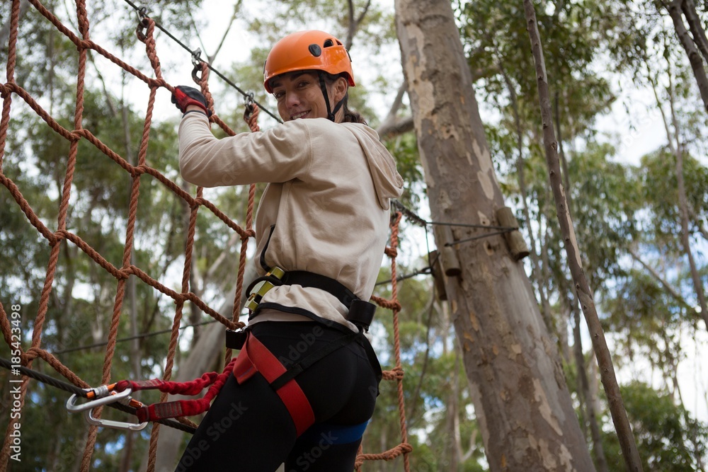 Woman wearing safety helmet climbing on a rope fence Woman wearing safety helmet climbing on a rope fence