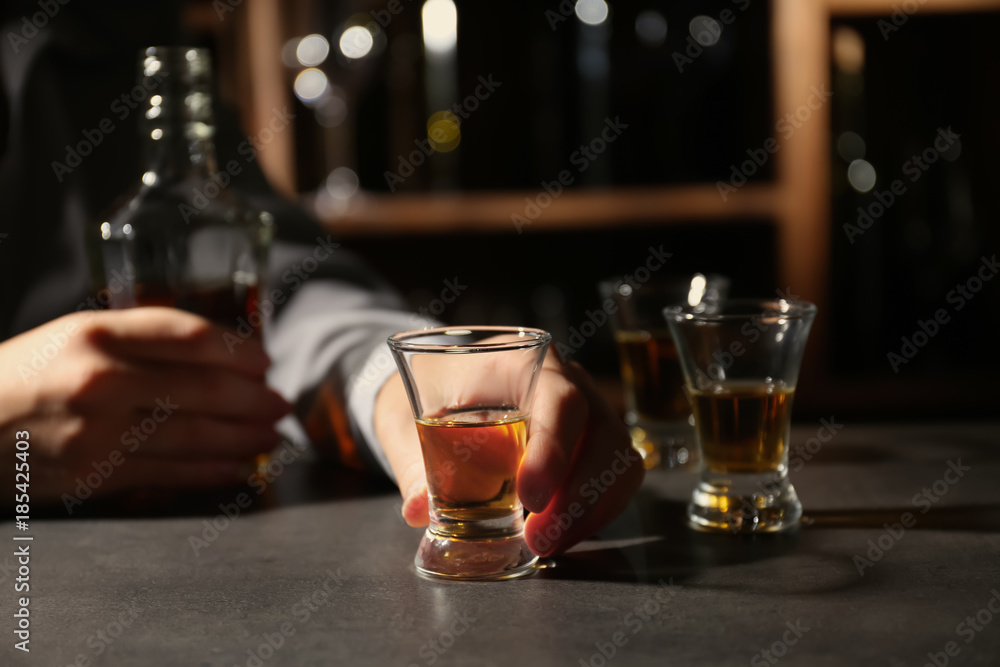 Woman with bottle and glass of brandy in bar. Alcohol dependence concept