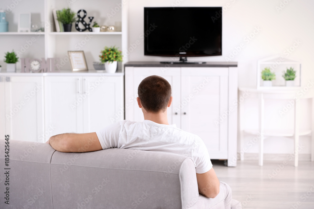 Young man watching TV on sofa at home