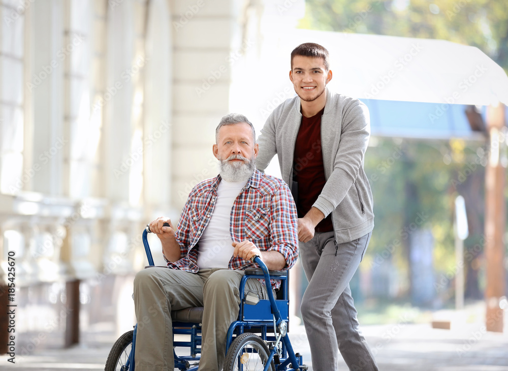 Young caregiver walking with senior man, outdoors Young caregiver walking with senior man, outdoors