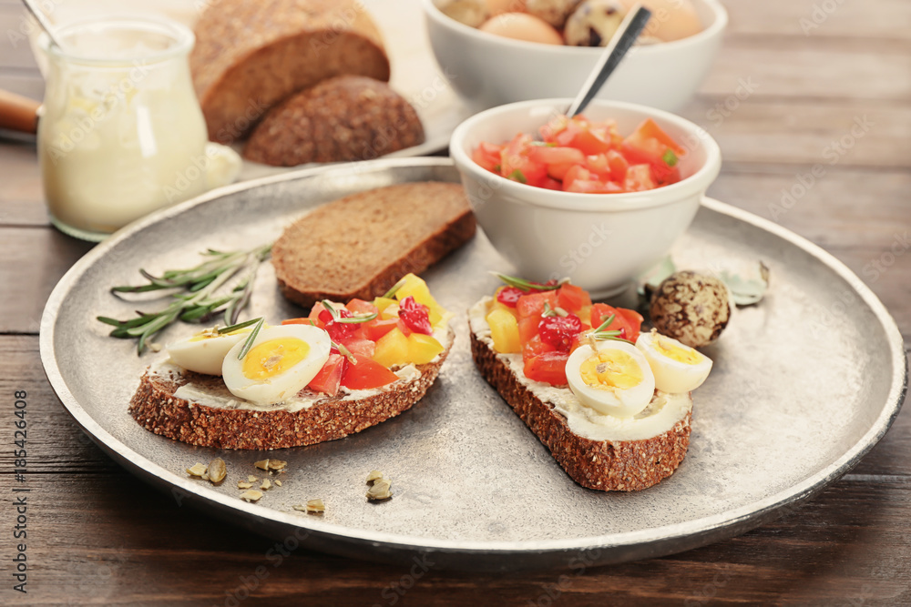 Tasty bruschettas with quail egg and vegetables on metal plate Tasty bruschettas with quail egg and vegetables on metal plate