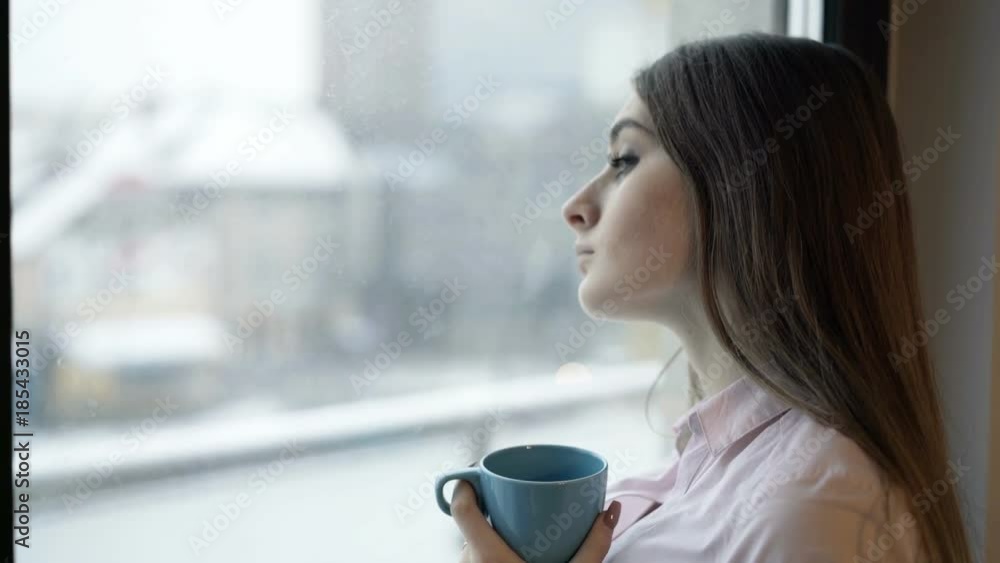 Sad, depressed woman drinking tea by the window at home
Sad, depressed woman drinking tea by the window at home