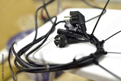 Black power cord and plug. Different skein of twisted wires. Bokeh.