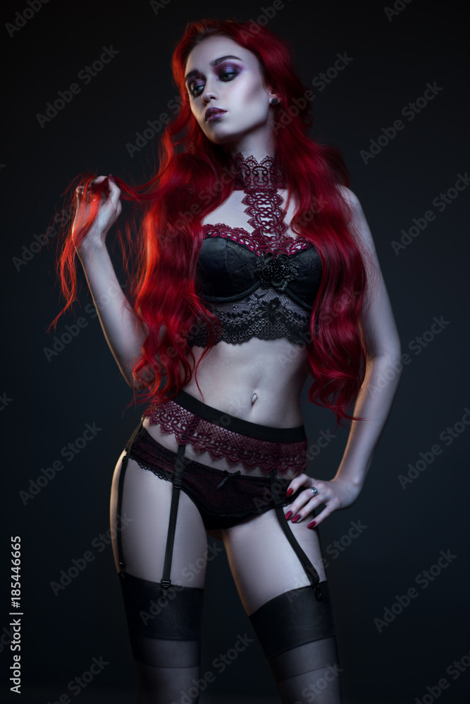 Beautiful gothic woman in lingerie posing at camera on black