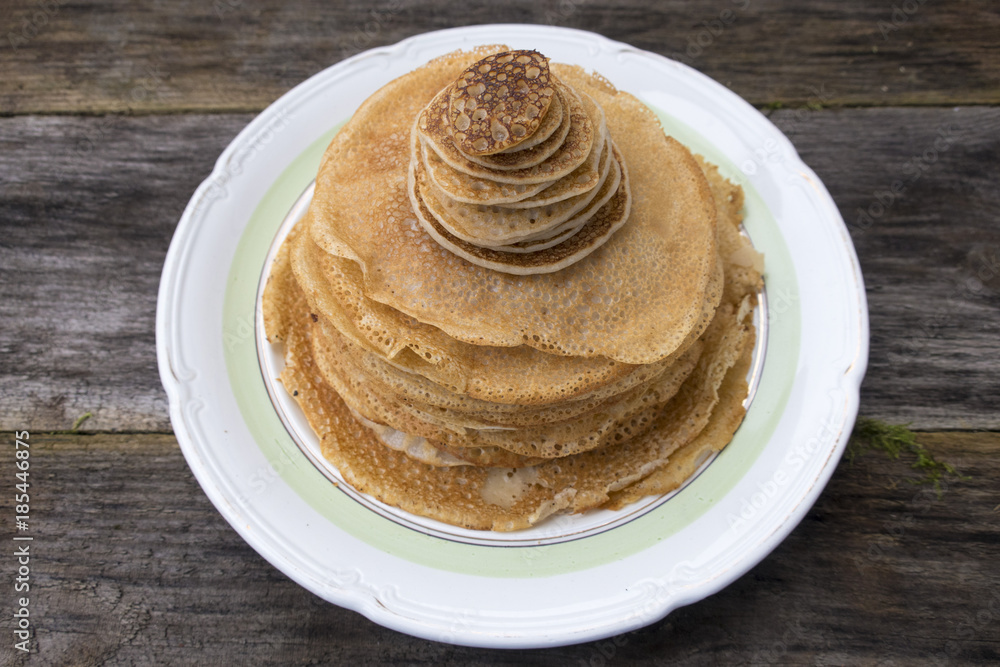 Large and small pancakes located on an old wooden table. Large and small pancakes located on an old wooden table.
