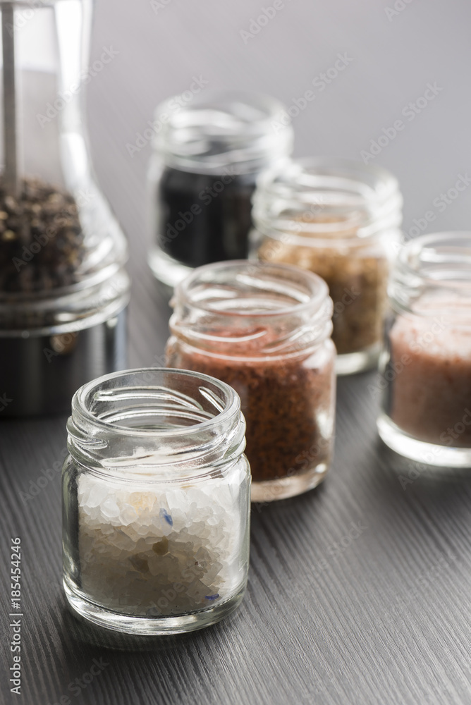 variety of natural and spicy salt into glass jars on black table variety of natural and spicy salt into glass jars on black table