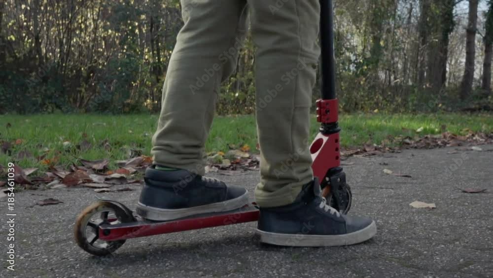 Cute curly haired African-American boy with afro hair rides on kick push scooter in autumn park Cute curly haired African-American boy with afro hair rides on kick push scooter in autumn park