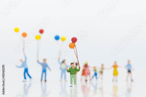Miniature people: children hold balloons, and play together, using as background International day of families concept.