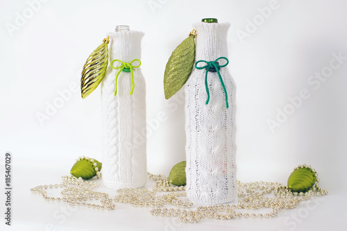 Two white knitted bottle covers placed on a white background