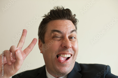 Businessman grimacing and showing peace sign