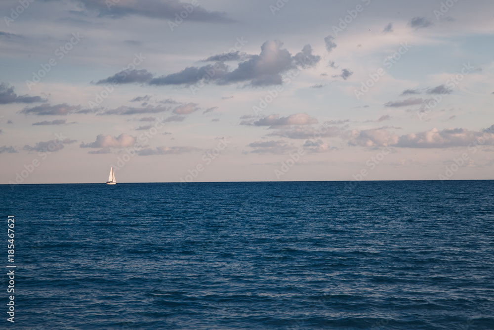 Seascape view of lonely Sail and sea at sunset on winter season - blue sky Seascape view of lonely Sail and sea at sunset on winter season - blue sky