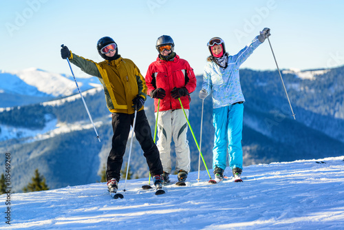 Three happy skiers having fun on winter ski slope photo