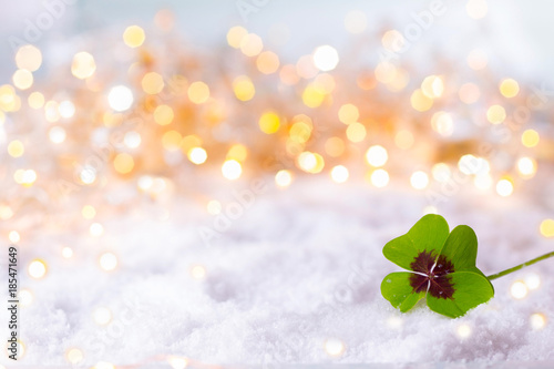 New Year Background  -  Four-leafed clover in snow landscape with bokeh lights