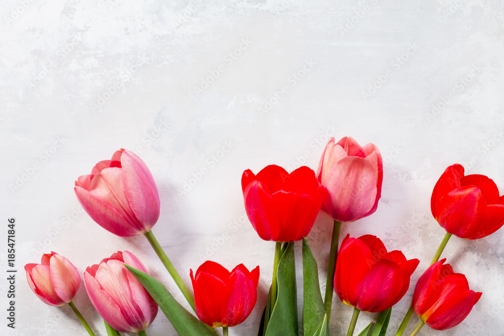 Fototapeta premium Background Valentine's Day or wedding. Red and pink tulips bouquet on a gray stone background. The apartment was lying. Top view with copy space.