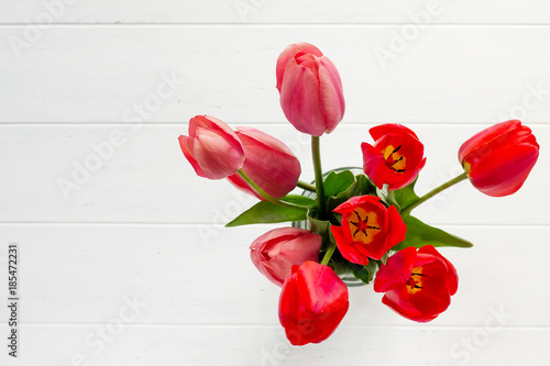 Background wedding or Valentine's Day. Red and pink tulips bouquet on a wooden table. The apartment was lying. Top view with copy space.