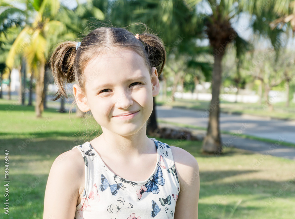 Smiling little girl with ponytails among palm trees in Thailand beautiful portrait. Travel concept. Text space Smiling little girl with ponytails among palm trees in Thailand beautiful portrait. Travel concept. Text space