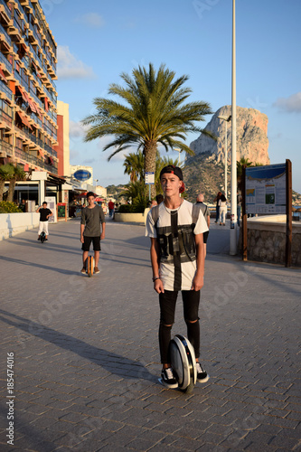 Boys are enjoying riding Monowheels scooters on a beach promenade photo