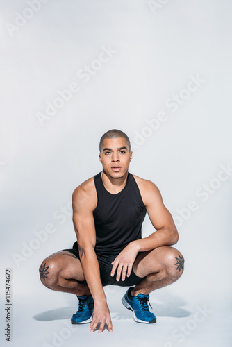 Fotografia sportive african american squatting and looking at camera