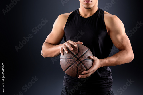 cropped shot of african american basketball player with ball on black