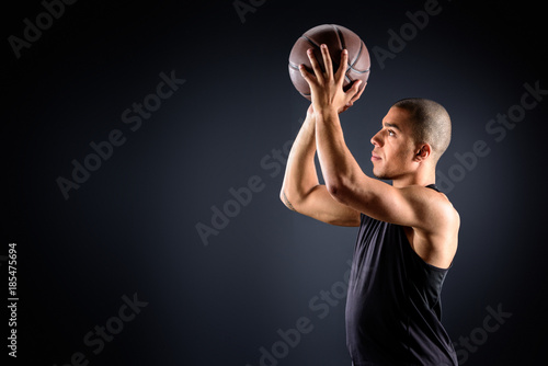 side view of african american basketball player throwing ball on black