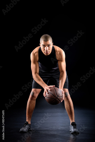 concentrated african american basketball player with ball on black