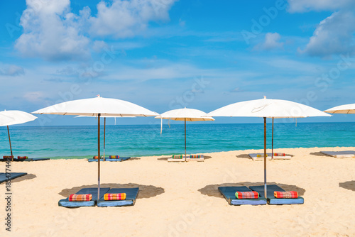 Idyllic beach relaxing concept with white parasols on sand