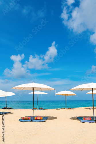 Idyllic beach relaxing concept with white parasols on sand