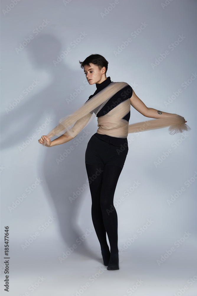 Obraz premium An unusual girl with short hair in all black with beige cloth