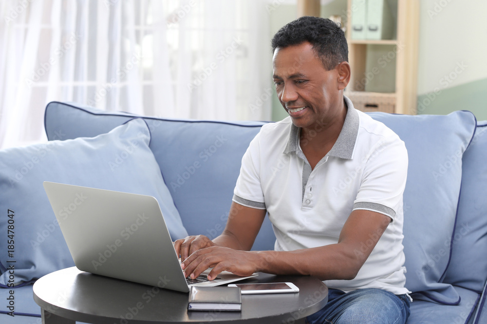 Mature African-American man using laptop at home