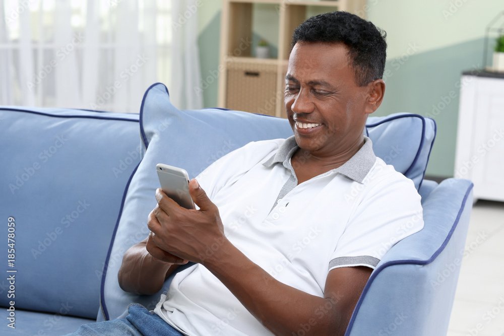 Mature African-American man using mobile phone at home