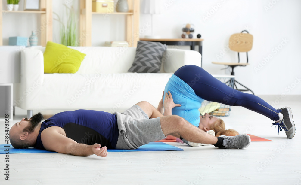 Overweight couple doing exercises at home Overweight couple doing exercises at home