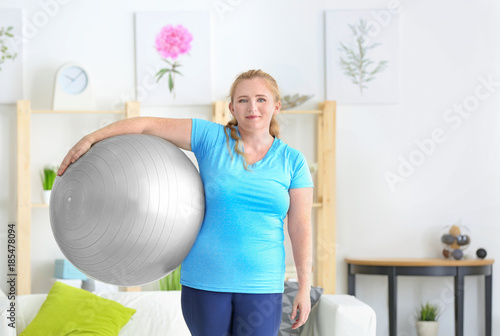 Overweight woman with fitness ball at home