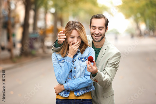 Fotografi Young man with engagement ring making proposal to his beloved girlfriend outdoor
