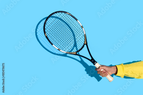 Close-up view of male hand holding tennis racket on blue background © LIGHTFIELD STUDIOS