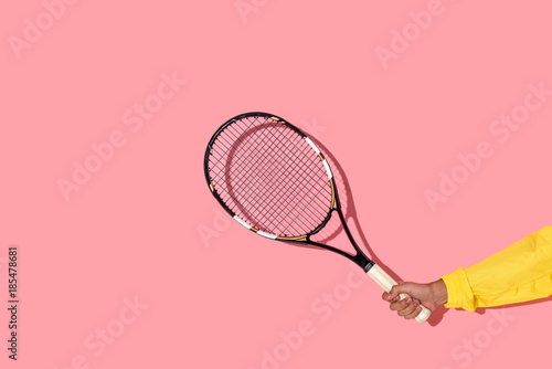 Fotografia Close-up view of male hand holding tennis racket on pink background
