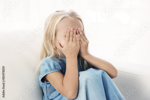Helpless little girl crying indoors. Child abuse concept